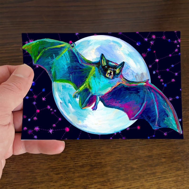 Puede incluir: Un murci&eacute;lago vibrante de colores ne&oacute;n vuela sobre un fondo de luna llena y cielo estrellado. Las alas del murci&eacute;lago son una mezcla de azul, verde y morado, con un cuerpo negro y una nariz rosa brillante. La luna es blanca con un brillo azul claro, y las estrellas son rosas y moradas.