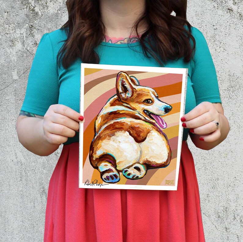 May include: A colourful painting of a corgi dog with a brown and white coat, sitting with its back to the viewer. The dog is on a background of brown and orange stripes. The painting is signed "Robert Phelps".
