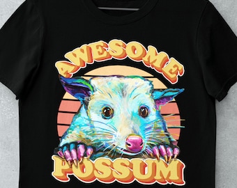 May include: A black t-shirt with a retro-style graphic of a possum with the text "Awesome Possum" in yellow letters.