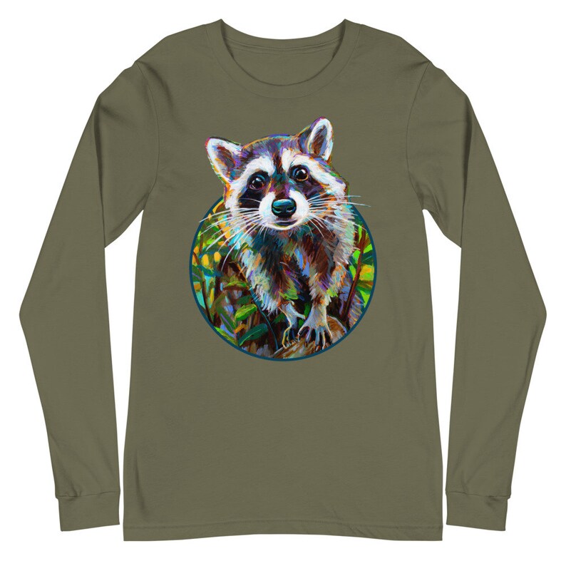 May include: Olive green long-sleeve shirt featuring a colorful raccoon illustration within a circular frame. The raccoon is depicted with vibrant brushstrokes, showcasing a mix of blues, browns, and whites. The design is centered on the shirt, offering a unique and artistic look.