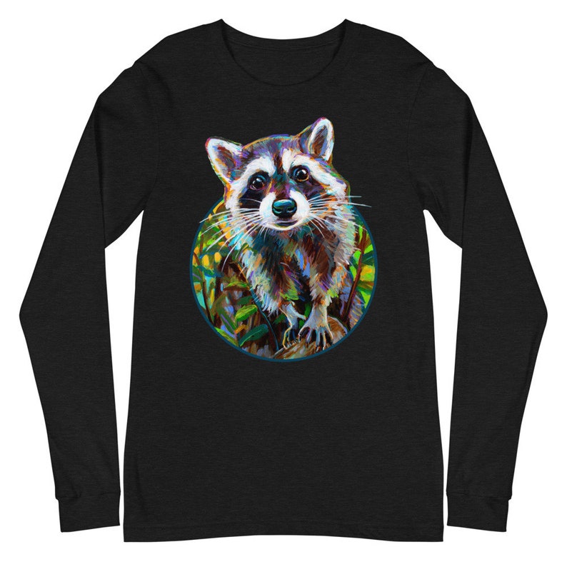 May include: Black long-sleeve shirt featuring a colorful raccoon illustration within a circular frame. The raccoon has a detailed, artistic design with shades of brown, white, and blue. The shirt is made of a soft material.