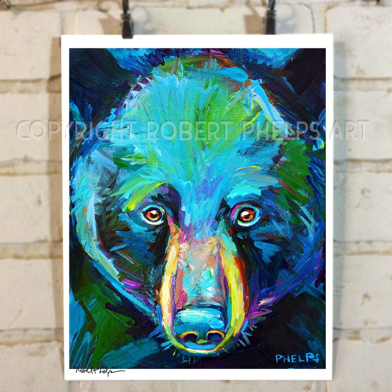 May include: A close-up painting of a black bear's face. The bear's fur is painted in shades of blue, green, and purple. The bear's eyes are orange, and its nose is pink. The painting is signed "Robert Phelps" in the bottom right corner.