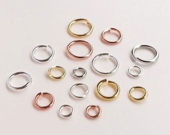 May include: Assortment of jump rings in silver, gold, and rose gold. The jump rings are various sizes and are arranged on a white background.