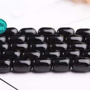 May include: A strand of black oval-shaped beads. The beads are smooth and glossy.