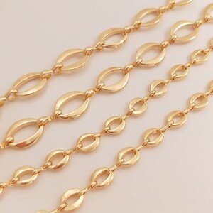 May include: Four strands of gold-colored chain with oval links of varying sizes. The chains are arranged diagonally across a light background. The chains are likely for jewelry making or crafting.