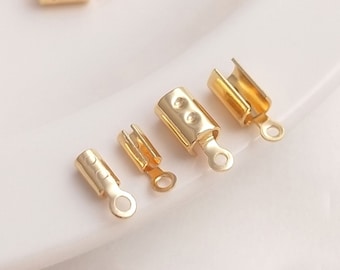 May include: Gold-toned metal end caps for cords or jewelry making. The end caps have a cylindrical shape with a small loop at the end. There are five end caps in the image, each with a slightly different size.