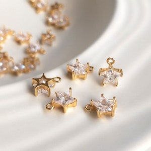 Puede incluir: Encantos dorados en forma de estrella con acentos de cristal transparente. Los encantos tienen un bucle para sujetar a joyas u otras artesan&iacute;as.