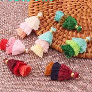 May include: Assortment of colorful multi-layered tassel trims with gold accents. The tassels are made of soft yarn and are perfect for adding a touch of handmade charm to your craft projects.