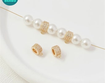 May include: Two gold-toned bead caps with clear rhinestone accents. The caps are shown on a white surface with a strand of white pearls and gold wire.