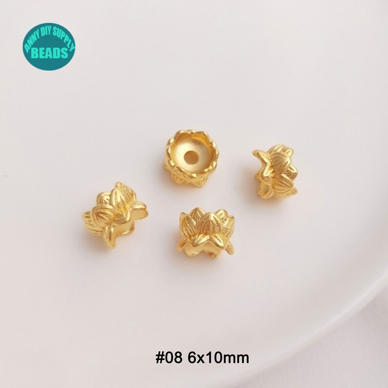 May include: Gold-colored lotus flower-shaped beads. The beads are made of metal and have a detailed floral design. The image includes four beads, with the text "#08 6x10mm" at the bottom. The beads are approximately 0.24 x 0.39 inches.