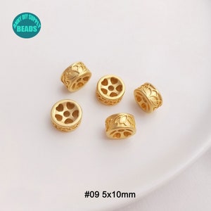 May include: Gold-colored metal beads with floral and heart-shaped cutouts. The beads are cylindrical, measuring 5mm x 10mm. The image includes the text "#09 5x10mm" and a logo that says "Anny DIY Supply Beads".