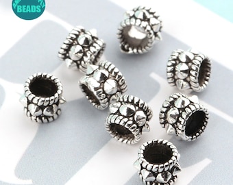 May include: Eight silver-toned metal beads with a textured design and small spikes. The beads are round and have a hole in the centre.