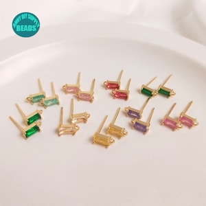 Könnte beinhalten: Sortiment an goldfarbenen Ohrring-Fundamenten mit bunten rechteckigen Steinen. Die Steine sind grün, rosa, rot, lila und gelb.