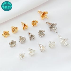 May include: A collection of gold and silver-colored flower-shaped beads. The beads vary in design, including rose and bell flower shapes. The image includes a teal circle with the text "ANNY DIY SUPPLY BEADS".