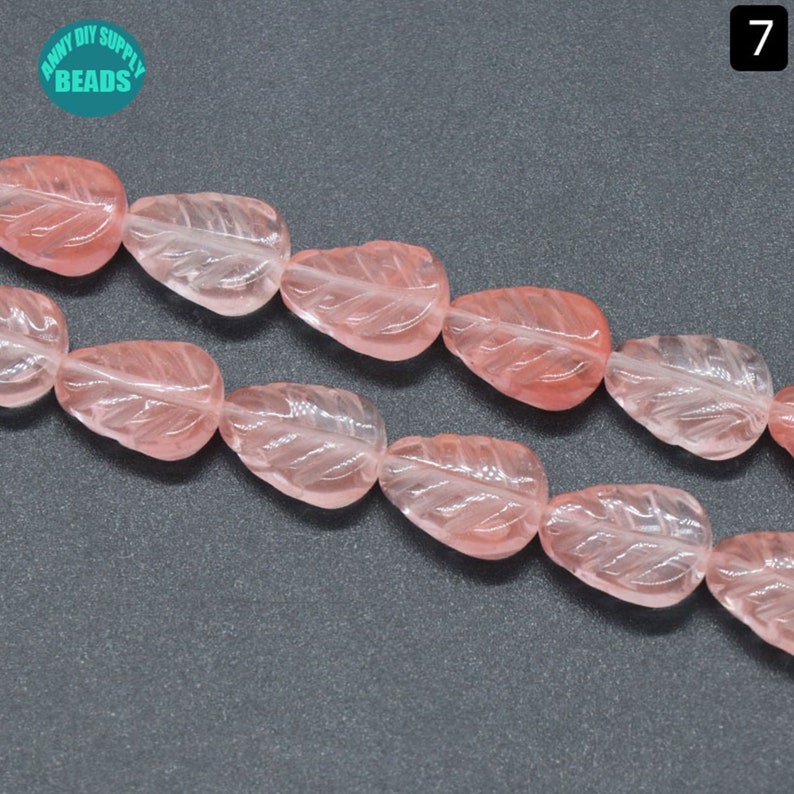 May include: A strand of pink leaf-shaped gemstone beads. The beads are translucent and have a carved leaf design.