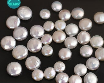 May include: A collection of white round pearl beads with an iridescent sheen. The beads are scattered on a black surface.