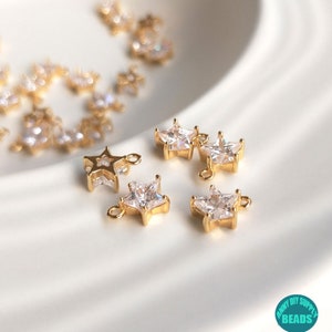 Puede incluir: Encantos dorados en forma de estrella con acentos de cristal transparente. Los encantos tienen un bucle para sujetar a joyas u otras artesan&iacute;as.