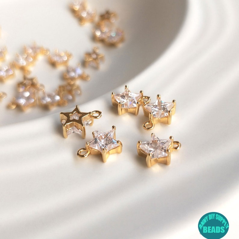 Puede incluir: Encantos dorados en forma de estrella con acentos de cristal transparente. Los encantos tienen un bucle para sujetar a joyas u otras artesan&iacute;as.