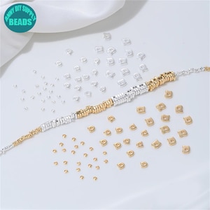 Pode incluir: Uma variedade de contas para fazer joias em tons de prata e ouro. As contas estão espalhadas ao redor de uma pulseira parcialmente montada. A imagem inclui um círculo turquesa com o texto "ANNY DIY SUPPLY BEADS".