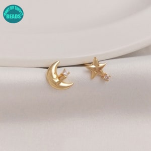 May include: A pair of gold-tone earrings featuring a crescent moon and a star design. Each earring has a small clear rhinestone accent.
