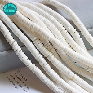 May include: White shell beads, strung together in a long strand. The beads are small and round, with a slightly irregular shape. They are perfect for making jewellery or other crafts.