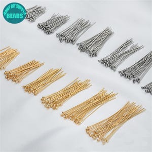 May include: An assortment of gold and silver-colored head pins, ideal for jewelry making and crafting. The pins have a small ball at the top and a long, straight wire. The image includes the text "ANNY DIY SUPPLY BEADS".