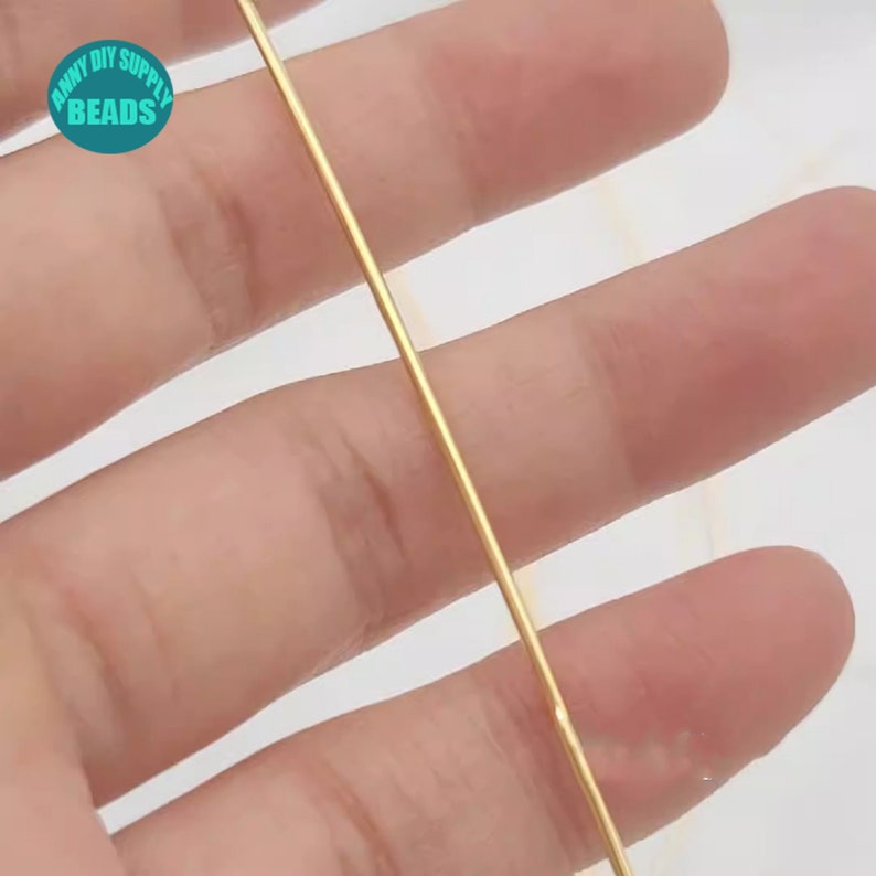 Pu&ograve; includere: Primo piano di un filo dorato, tenuto tra due dita. Il filo &egrave; sottile e flessibile, e sembra essere fatto di metallo.