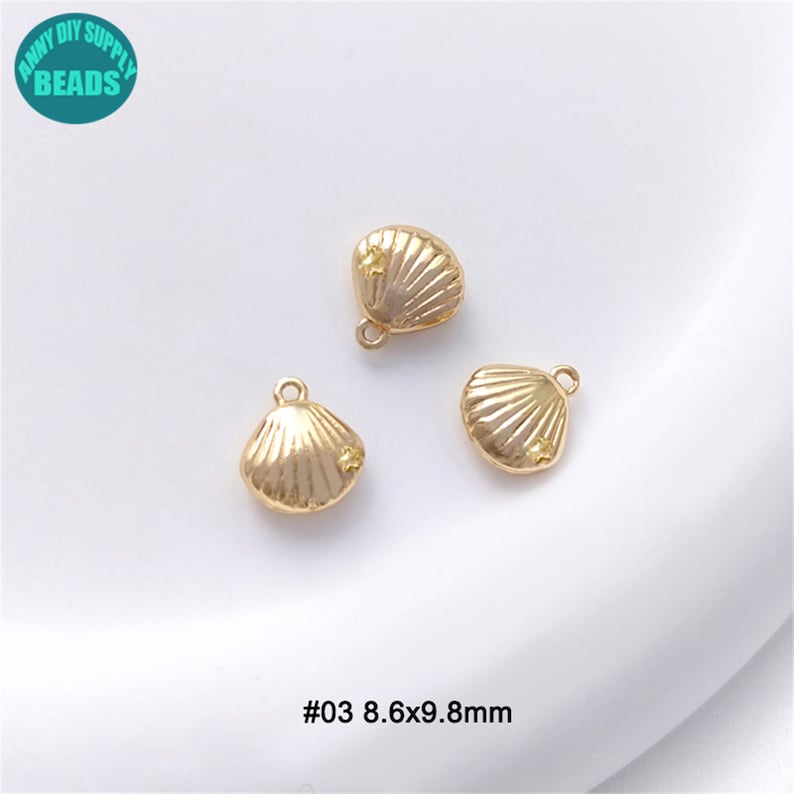 Puede incluir: Tres abalorios de concha de mar de color dorado con un peque&ntilde;o detalle de estrella. Cada abalorio mide 8,6 por 9,8 mil&iacute;metros. #03