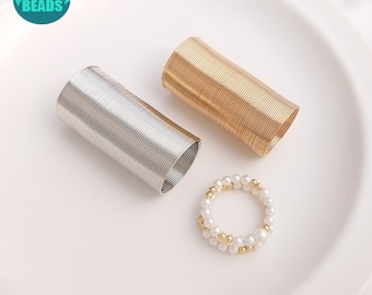 May include: Two spools of wire, one gold and one silver, and a pearl and gold bead ring. The spools are coiled and ready to be used for jewelry making.