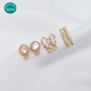 May include: A set of gold-tone earring findings with clear crystal accents. The set includes two round findings, two rectangular findings, and two bar findings.
