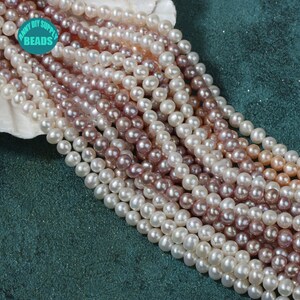 May include: A strand of white, pink, and purple pearl beads. The pearls are round and smooth, and they are strung on a clear thread. The beads are arranged in a loose, flowing pattern.