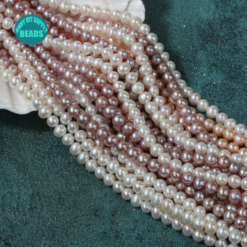 May include: A strand of white, pink, and purple pearl beads. The pearls are round and smooth, and they are strung on a clear thread. The beads are arranged in a loose, flowing pattern.