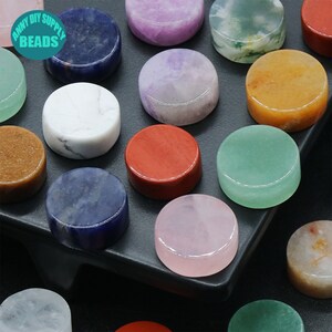 K&ouml;nnte beinhalten: Sortiment runder, polierter Edelsteinkabochons in verschiedenen Farben, darunter Gr&uuml;n, Lila, Rosa, Rot, Braun, Wei&szlig; und Blau. Die Cabochons sind auf einer schwarzen Oberfl&auml;che angeordnet. "Anny DIY Supply Beads" ist auf einem wei&szlig;en Etikett in der oberen linken Ecke des Bildes aufgedruckt.