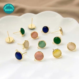 Puede incluir: Surtido de 10 engastes de pendientes de tono dorado con cabujones de diferentes colores. Los cabujones son en tonos de verde, azul, rosa y blanco. Los engastes de pendientes tienen un poste y un bucle.