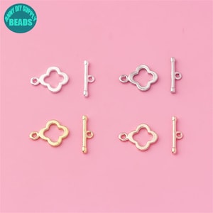 May include: Four pairs of silver and gold toggle clasps with a clover design. Each clasp has a bar and a clover-shaped piece.