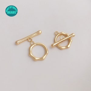 Può includere: Due chiusure a scatto in metallo dorato con un anello rotondo testurizzato e una barra dritta. Le chiusure sono utilizzate per la creazione di gioielli.