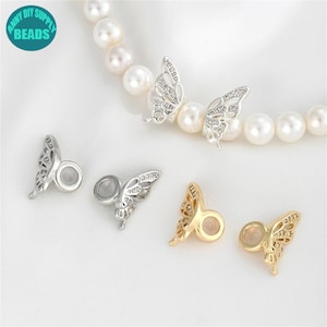 May include: Two pairs of silver and gold butterfly charm beads with clear rhinestones. The beads have a hole in the centre for stringing on a necklace or bracelet.