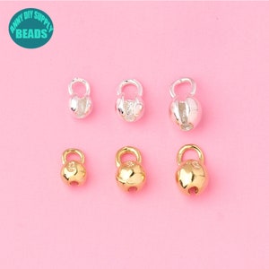 Pode incluir: Seis argolas de salto de prata e ouro com uma bola redonda no topo. As argolas de salto estão abertas e prontas para serem presas a uma corrente ou outras joias.