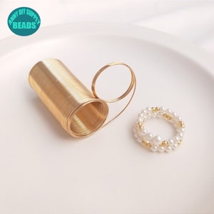 May include: A gold coil of wire and a gold and white pearl bracelet. The bracelet is made of small white pearls and gold beads.