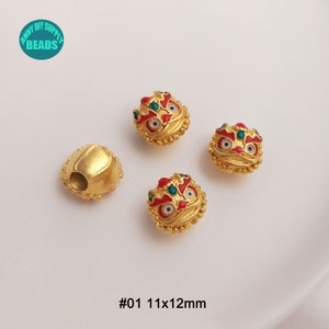 May include: Gold-colored metal beads with a lion-like design, featuring red, green, and white accents. One bead is a plain gold shape. The beads are approximately 0.43 x 0.47 inches in size. The text "#01 11x12mm" is visible.