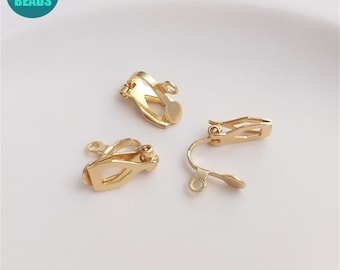 May include: Three gold-toned earring clips. The clips are designed to be worn on the earlobe and have a small loop at the top for attaching earrings.