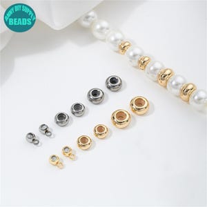 Peut inclure: Un assortiment de perles pour la fabrication de bijoux en tons or et argent. Les perles sont rondes et cylindriques, de tailles variées. Un rang de perles avec des accents dorés est également présent. Le logo "ANNY DIY SUPPLY BEADS" est visible.