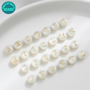 May include: White round beads with gold letters spelling out the alphabet A through Z.