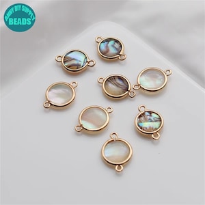 Könnte beinhalten: Acht goldfarbene runde Muschel-Anhänger mit jeweils zwei Sprungringen. Die Anhänger haben ein schillerndes Abalone-Muschel-Design.