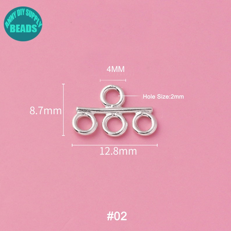 May include: Silver-toned metal connector with four loops. The connector measures 12.8 mm wide, 8.7 mm high, and has a 4 mm loop at the top. The hole size is 2 mm. #02