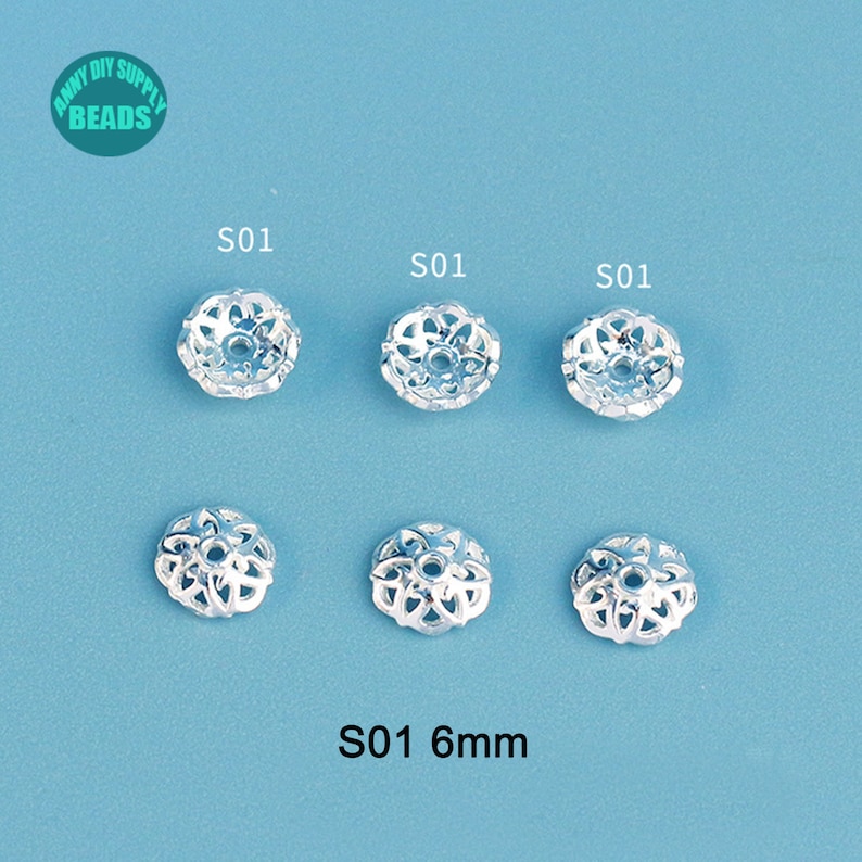 May include: Six silver-colored, open-work bead caps, each 6mm in diameter, are arranged on a light blue surface. The bead caps have a floral design. The text "S01" is above each bead cap. The text "S01 6mm" is at the bottom.