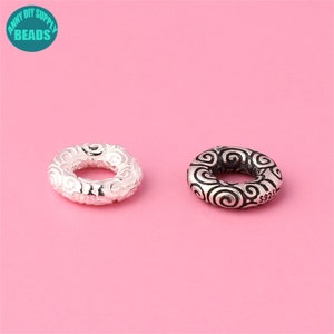 Può includere: Due perline distanziatrici in argento con un motivo a spirale. La perla a destra ha l'iscrizione "S925" sul lato.