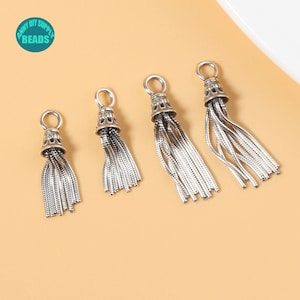 Puede incluir: Cuatro abalorios de borla plateados de diferentes tamaños. Las borlas están hechas de cadenas finas y enlazadas y tienen una parte superior decorativa.