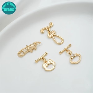 May include: Four gold-tone metal toggle clasps with different decorative charms. The charms include a cloud with a rhinestone, an elephant, a cloud, and a swirl design.