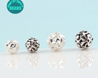 May include: Four silver filigree beads of varying sizes. The beads are round and have a delicate, intricate design.